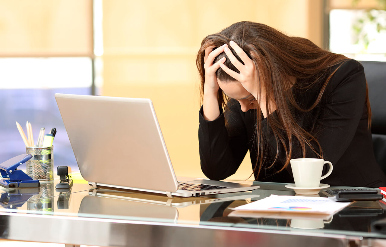 Mulher com mãos na cabeça em um escritório demonstrando estresse no trabalho