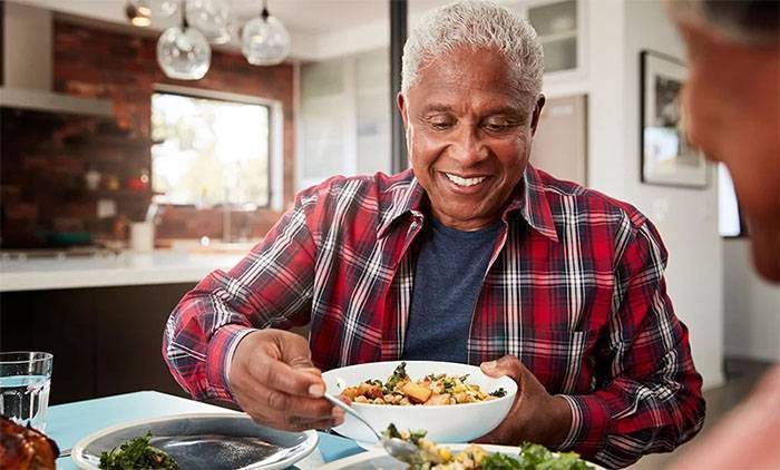 Homem idoso sorrindo prestes a comer uma refeição
